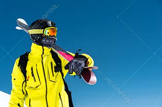 Skier standing on a slope. Man in a light suit, the helmet and mask in skiing is to ski. In the background snow-capped