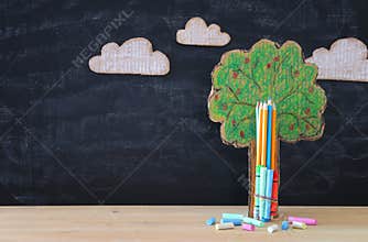 Back to school banner. tree of knowledge and pencils in front of classroom blackboard.