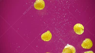 A fresh raspberries are splashing into water on pink background.