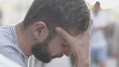 Overwhelmed man sitting in street, young male shocked by bad news, slow-mo