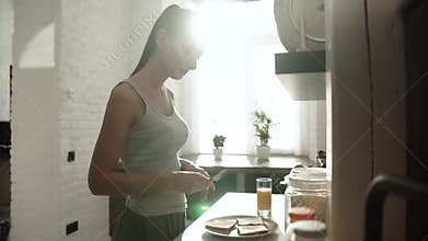 Woman Cooking Toast With Butter For Breakfast On Modern Kitchen