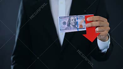 Financial consultant holding dollar banknotes showing thumbs down, falling