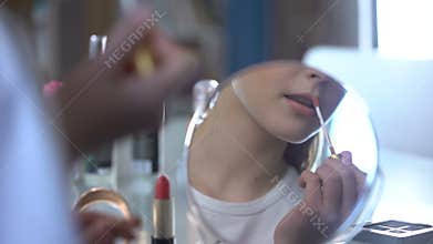 Girl trying moms lipsticks enjoying her look in mirror, adolescence, femininity