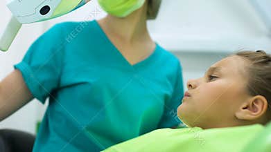 Female dentist treating tooth to little girl, polishing enamel, caries removal