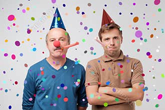 Unhappy guys are on party. Son and father are upset and do not want to have fun.