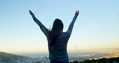 Woman standing with arms outstretched on top of the mountain 4k