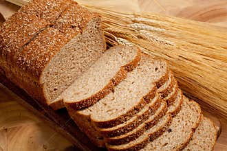 A loaf of bread and shock of wheat on wood