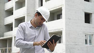 Engineer man with tablet talking on mobile phone and checking building technology process