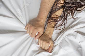 Couple hands pulling white sheets in ecstasy, orgasm. Concept of passion. Oorgasm. Erotic moments. Intimate concept. Sex