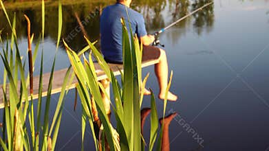 Man fishing in the pond on sunset