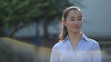 Young happy beautiful Asian businesswoman thinking outdoors