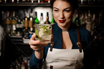 Bartender girl holding an fresh cocktail with lime and mint