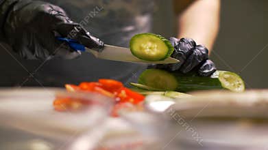 Chef hands cutting fresh cucumber on round pieces for cooking vegetable salad