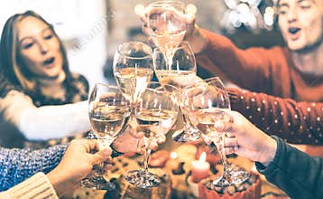 Friends group celebrating Christmas toasting champagne wine at home dinner party