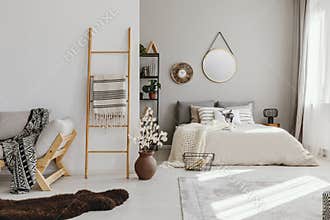 open space bedroom interior with window with curtains, mirror and clock on the wall, ladder with blanket,