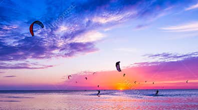 Kite-surfing against a beautiful sunset. Many silhouettes of kit