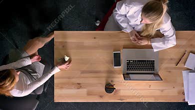 Dolly shot of top down view of formally-dressed woman, rejecting to take money, given by another woman