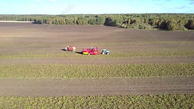 Aerial view truck pulls away from potato combine on field