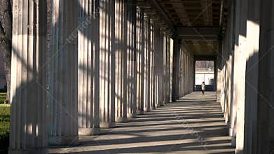 Young woman teenage girl mixed race female wearing camouflage jacket, walking through columns passageway during the day