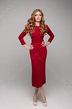 Gorgeous young woman in elegant evening red dress and beige heels.