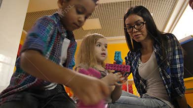 Teacher with diverse kids playing with didactic toys
