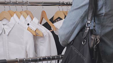 A woman in a store chooses clothes and steals her discreetly, putting them in a bag