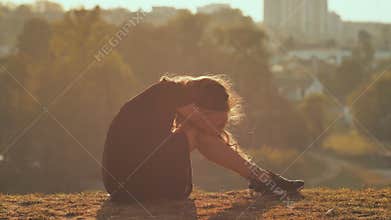 Sad girl silhouette sit alone in the grass so lonely and cry.