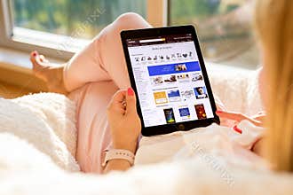 Riga, Latvia - July 21, 2018: Woman shopping for books on Amazon website on iPad.