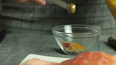 Woman cooking salmon fish at home - preparing spices