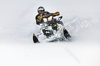 In deep snowdrift snowmobile rider make fast turn. Riding with fun in deep snow powder during backcountry tour. Extreme sport