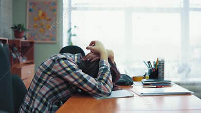 Young brunette woman sits at a table in a state of panic with a headache.