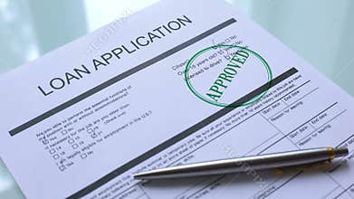 Loan application document approved, hand stamping seal on official paper closeup