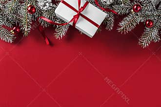 Creative layout frame made of Christmas fir branches, pine cones, gifts, red decoration on red background.