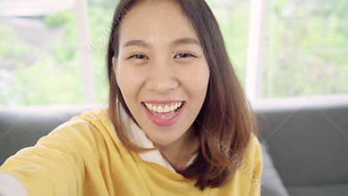 Asian blogger woman using smartphone recording vlog video in living room at home,female enjoy funny moment.