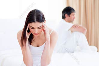 Sad couple having an argument sitting on bed