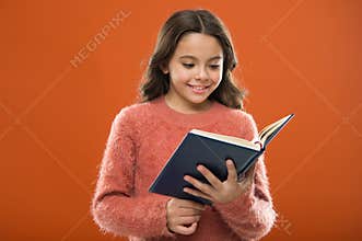 Reading activities for kids. Girl hold book read story over orange background. Child enjoy reading book. Book store
