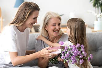 Happy grandma thanking grandchild and grown daughter for flowers