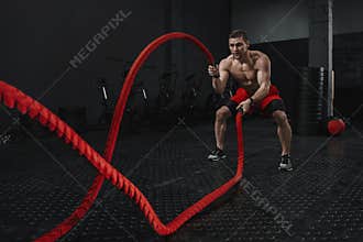 Crossfit battle ropes exercise during atlete training at the workout gym