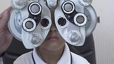 Little boy`s eye examination at optometrist ophthalmologist using phoropter close up. Hand of the doctor changing glass