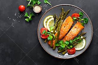 Grilled salmon fish steak, asparagus, tomato and corn salad on plate. Healthy dish for lunch
