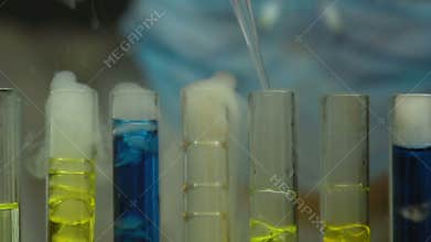 Lab worker dripping liquid into boiling test tubes, chemical reaction monitoring