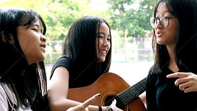 Asian teenager playing guitar and singing song