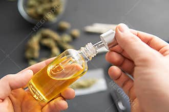Natural herb, close up, medical marijuana concept, CBD cannabis OIL. hemp product, Hand holding bottle