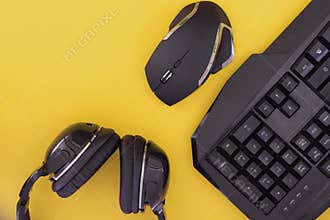 Black mouse, the keyboard, the headphones are isolated on a yellow background, the top view. gamer background