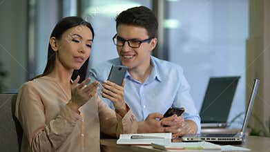 Two marketers testing work of new mobile app on smartphone, software engineering