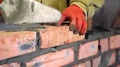 Bricklaying. Hands that put a brick on a construction site