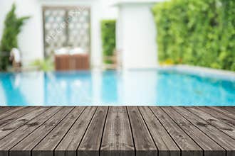 Empty wooden table in front with blurred background of swimming pool