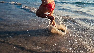 Slow motion of a little barefoot girl running on wet sand along the sea in the warm light of evening sun. Careless and
