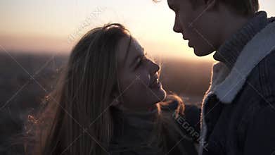 Close up footage of romantic young couple standing face to face backlit by the sun with flare effect while standing on