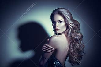 Sexy young woman portrait. Seductive brunette girl posing in darkness. Beauty glamour lady with long curly hair